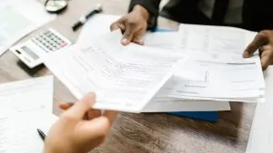 Pessoas trocando documentos de remessas internacionais em cima da mesa 